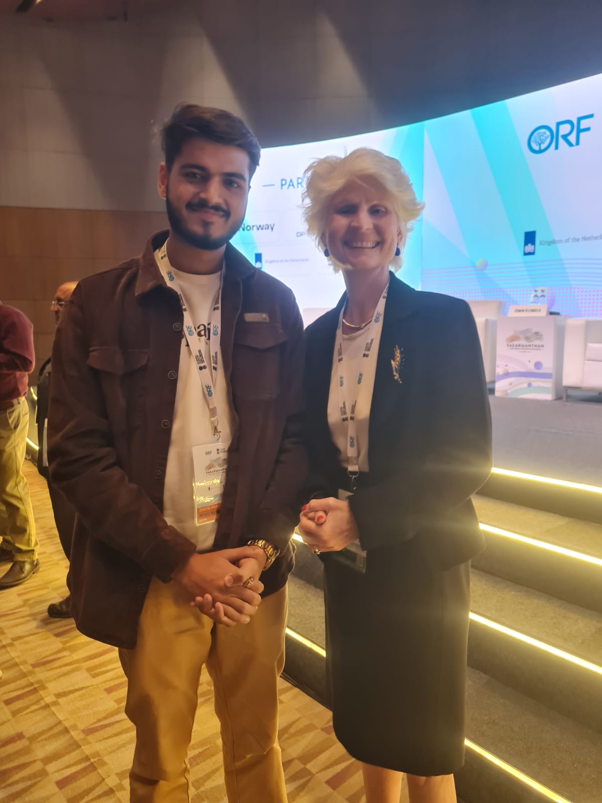 Akshat Mehrotra standing next to a female dignitary on stage.